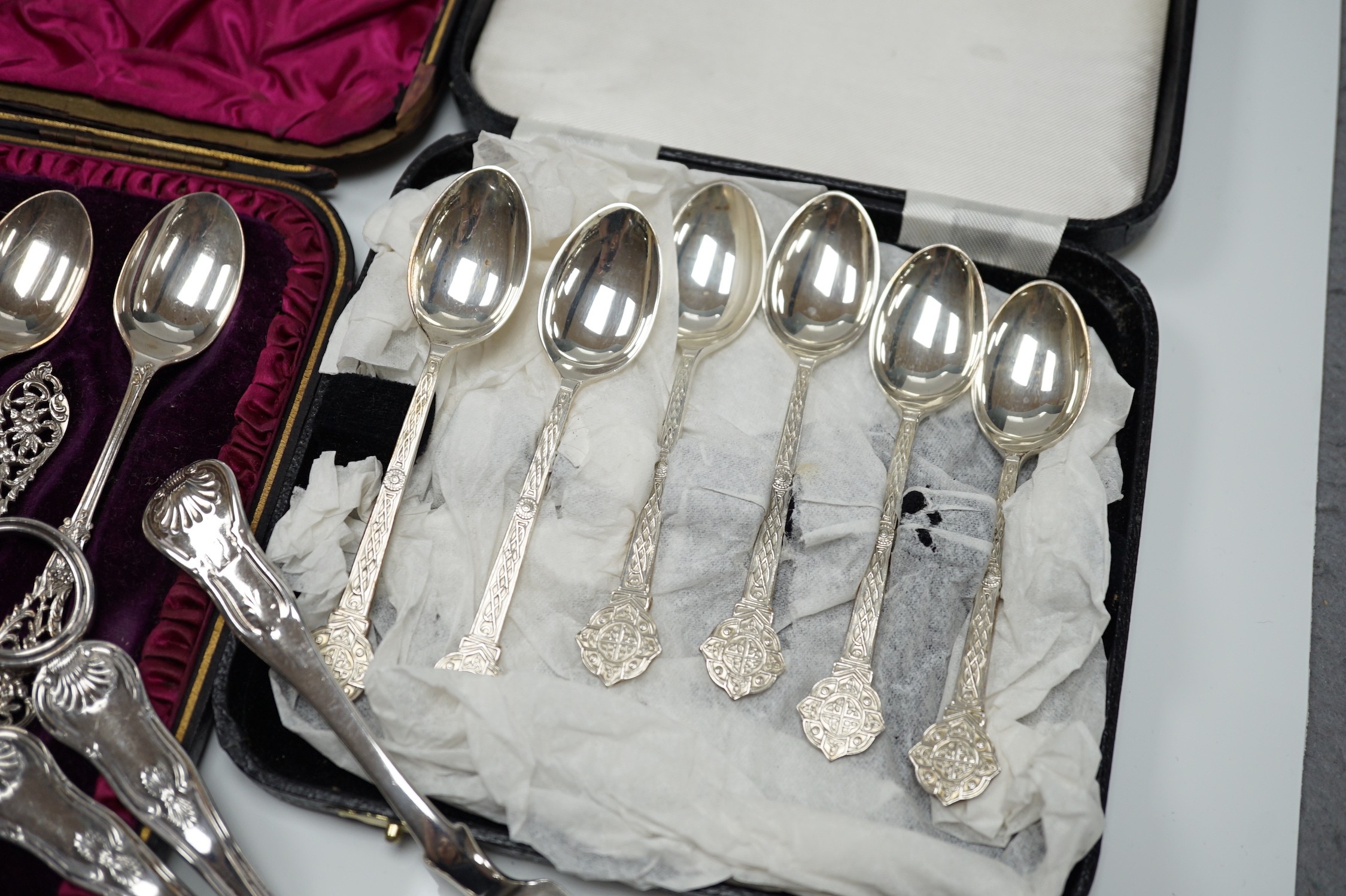 A cased set of twelve Victorian silver teaspoons, with pierced terminals by William Comyns, London 1889, with a damaged pair of matching sugar tongs, a cased set of six later teaspoons, a pair of George IV silver King's